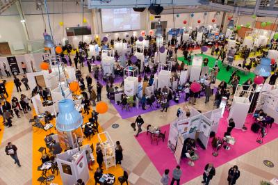 Salle circulaire avec tables rondes dressées, nappes grises et serviettes vertes, entourée de baies vitrées donnant sur des…