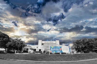 Salle circulaire avec tables rondes dressées, nappes grises et serviettes vertes, entourée de baies vitrées donnant sur des…