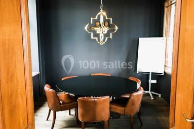 Personnes rassemblées sous une tente verte sur une terrasse, avec des plantes en pot et des clochers en arrière-plan.