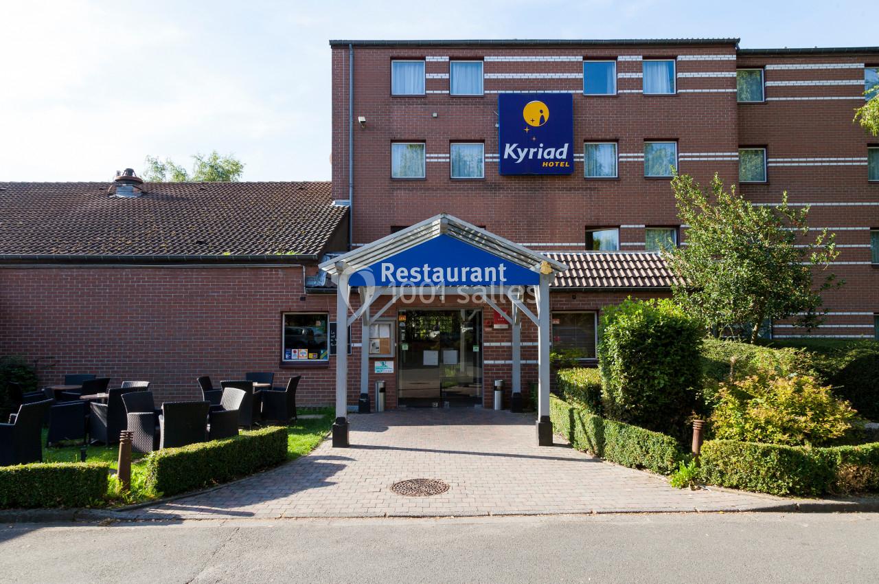 Entrée d'un hôtel-restaurant en briques rouges avec terrasse extérieure et enseigne visible.