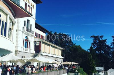 Salle de casino avec machines à sous illuminées, chaises noires et décor moderne sous un plafond sombre.