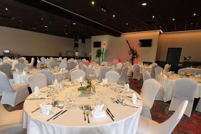 Salle de casino avec machines à sous illuminées, chaises noires et décor moderne sous un plafond sombre.