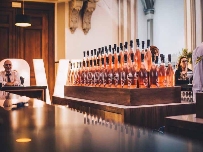 Alignement de bouteilles de vin rosé sur un comptoir en bois dans un espace intérieur élégant.