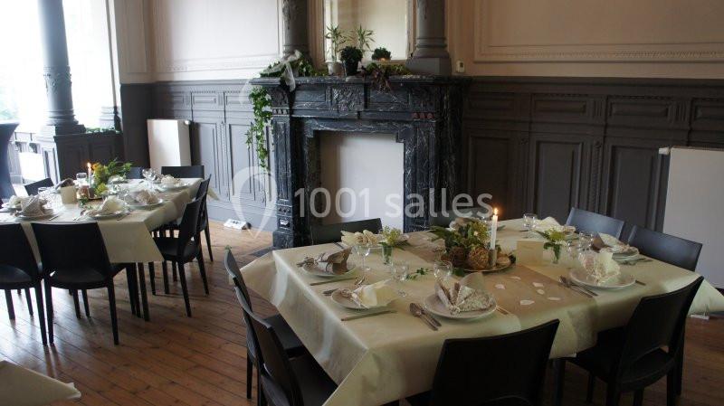Location salle Farciennes (Hainaut) - Château Oxyjeunes #15 Salle élégante avec tables dressées, nappes claires, décorations florales et cheminée en marbre noir en arrière-plan.