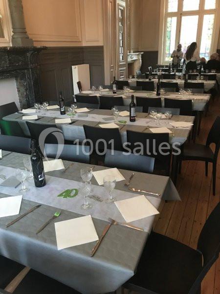 Location salle Farciennes (Hainaut) - Château Oxyjeunes #17 Salle à manger avec tables dressées, nappes grises, couverts, verres et bouteilles de vin, éclairée par des fenêtres.