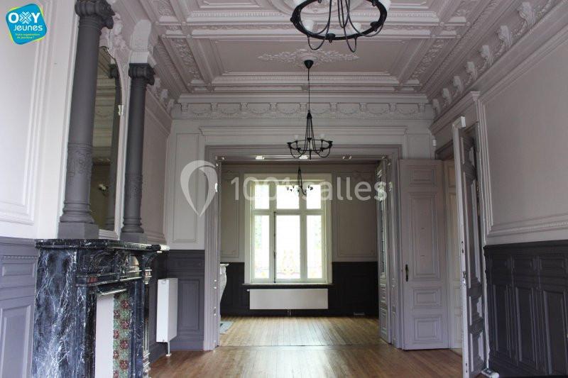 Location salle Farciennes (Hainaut) - Château Oxyjeunes #9 Intérieur d'une pièce lumineuse avec moulures au plafond, cheminée en marbre et parquet en bois clair.