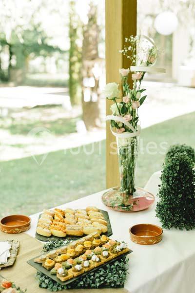 Table dressée en extérieur avec des plateaux de petits fours salés et un vase de fleurs décoratif.
