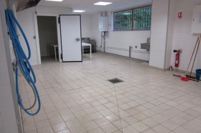 Salle lumineuse avec grandes fenêtres, mobilier en rotin gris et poutres apparentes, donnant sur un espace extérieur…