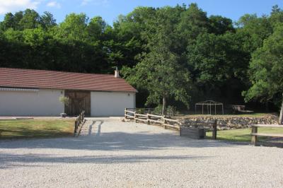 Salle lumineuse avec grandes fenêtres, mobilier en rotin gris et poutres apparentes, donnant sur un espace extérieur…