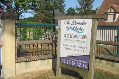 Salle lumineuse avec grandes fenêtres, mobilier en rotin gris et poutres apparentes, donnant sur un espace extérieur…