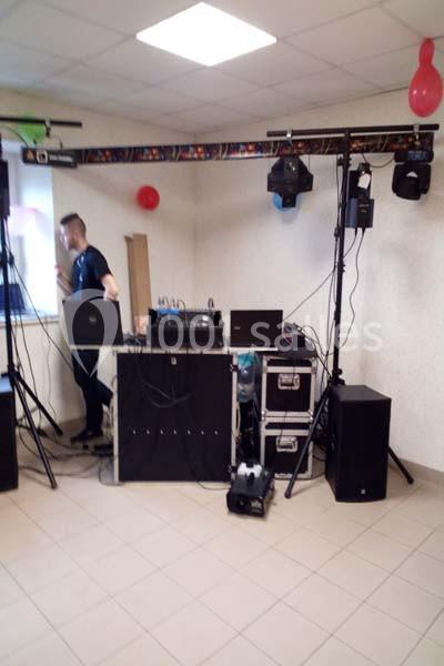 Équipement de sonorisation et éclairage installé dans une salle, avec un technicien en arrière-plan.