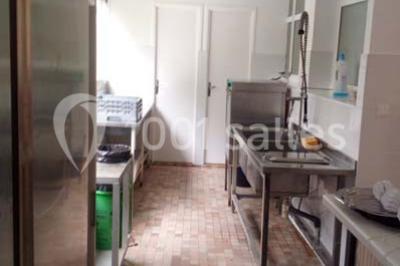 Miniature Location salle Trégomeur (Côtes-d'Armor) - Les Serres du Rodo #14 Évier double en inox avec robinet flexible, lave-vaisselle professionnel et sol en carrelage beige dans une cuisine.