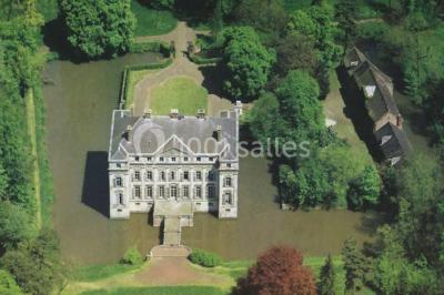 Salon lumineux avec parquet, mobilier classique, table ronde dressée au centre et lustre en cristal au plafond.