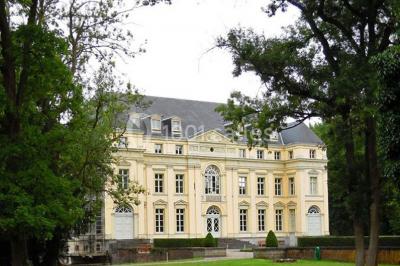 Salon lumineux avec parquet, mobilier classique, table ronde dressée au centre et lustre en cristal au plafond.