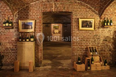 Salon lumineux avec parquet, mobilier classique, table ronde dressée au centre et lustre en cristal au plafond.