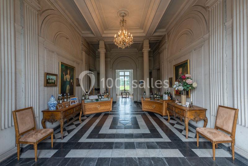 Intérieur d'une salle élégante avec sol en damier, mobilier ancien, tableaux et lustre au plafond.