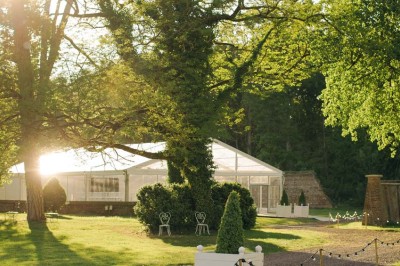 Salon lumineux avec parquet, mobilier classique, table ronde dressée au centre et lustre en cristal au plafond.