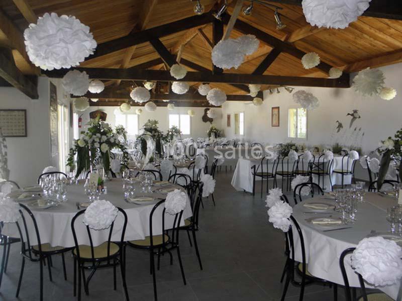 Location salle Arles (Bouches-du-Rhône) - Manade Allard #3 Salle de réception décorée avec des tables dressées, chaises noires et ornements blancs suspendus au plafond.