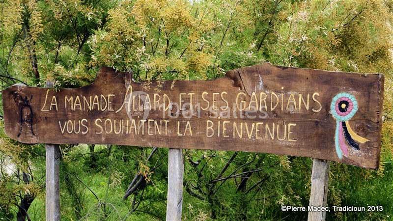 Location salle Arles (Bouches-du-Rhône) - Manade Allard #6 Panneau en bois gravé accueillant les visiteurs à la manade Allard, entouré de végétation.