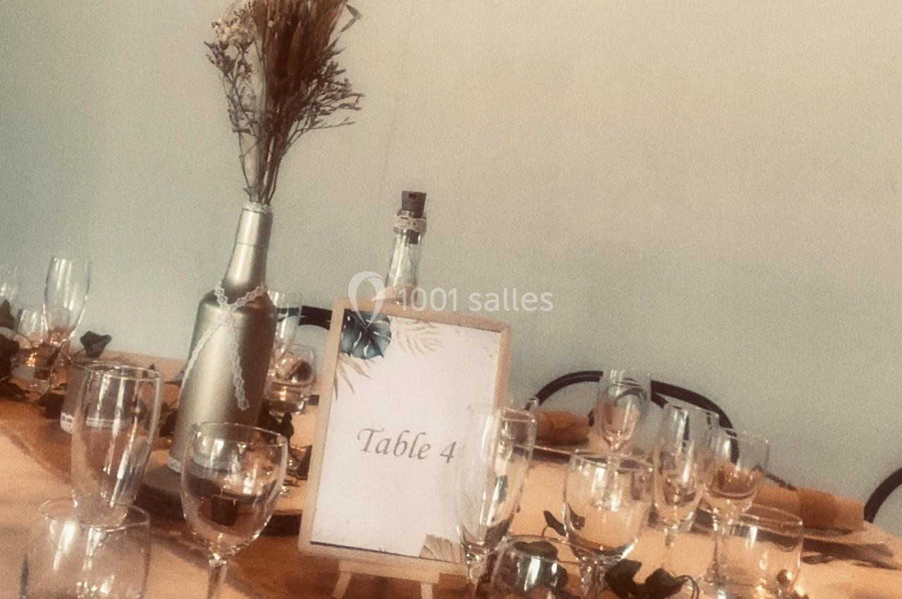 Location salle Arles (Bouches-du-Rhône) - Manade Allard #5 Table décorée avec des verres, une bouteille, un centre de table floral et un panneau indiquant ’Table 4’.