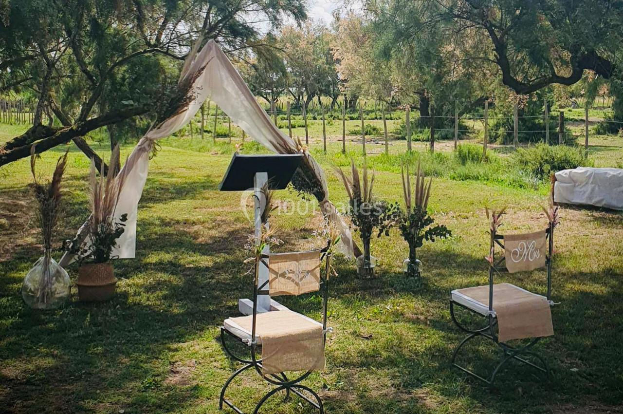 Location salle Arles (Bouches-du-Rhône) - Manade Allard #8 Chaises décorées et arche en tissu installées dans un jardin pour une cérémonie en plein air.