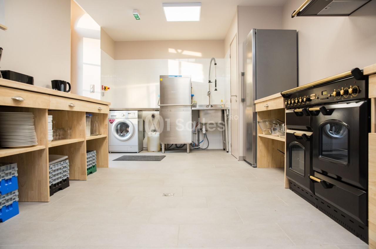 Cuisine équipée avec électroménagers, plan de travail en bois, lave-linge, lave-vaisselle et grand four noir.