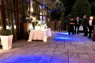 Parking extérieur de nuit, éclairé par des lumières jaunes et entouré d'arbres et de bâtiments.