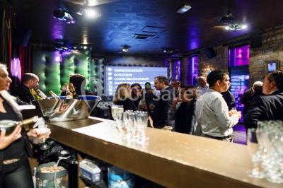 Parking extérieur de nuit, éclairé par des lumières jaunes et entouré d'arbres et de bâtiments.