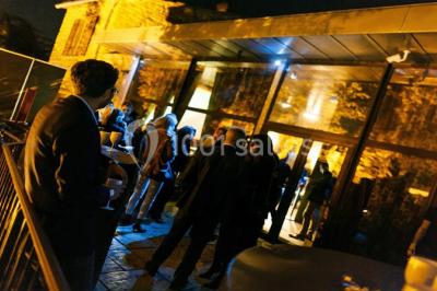 Parking extérieur de nuit, éclairé par des lumières jaunes et entouré d'arbres et de bâtiments.