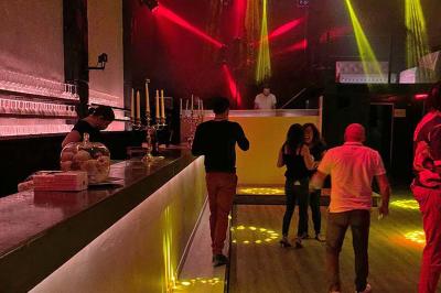 Parking extérieur de nuit, éclairé par des lumières jaunes et entouré d'arbres et de bâtiments.