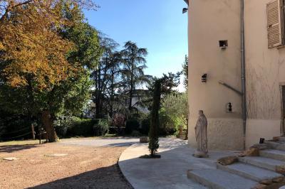 Parking extérieur de nuit, éclairé par des lumières jaunes et entouré d'arbres et de bâtiments.