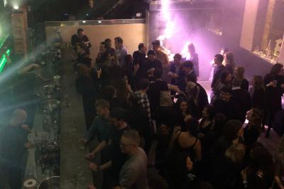 Parking extérieur de nuit, éclairé par des lumières jaunes et entouré d'arbres et de bâtiments.