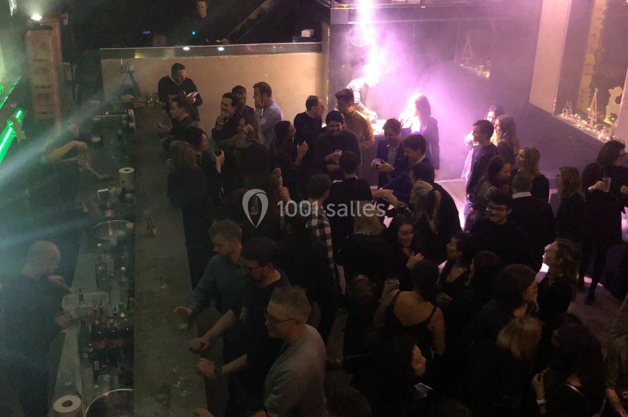 Vue plongeante d'une foule dans un bar ou une discothèque, avec éclairage tamisé et ambiance festive.