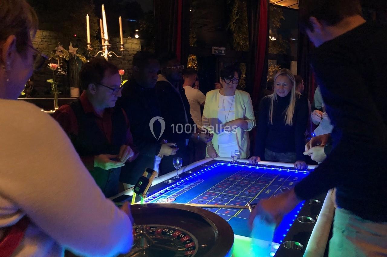Des personnes jouent autour d'une table de roulette éclairée dans une ambiance tamisée.
