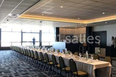 Vue d'une côte avec des falaises, des bâtiments en bord de mer et un ciel partiellement nuageux au crépuscule.