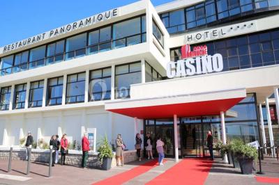 Vue d'une côte avec des falaises, des bâtiments en bord de mer et un ciel partiellement nuageux au crépuscule.
