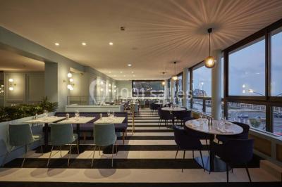 Vue d'une côte avec des falaises, des bâtiments en bord de mer et un ciel partiellement nuageux au crépuscule.