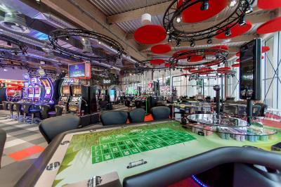 Bâtiment moderne en bord de rivière, entouré de verdure, avec un pont piétonnier au premier plan.