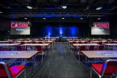Bâtiment moderne en bord de rivière, entouré de verdure, avec un pont piétonnier au premier plan.