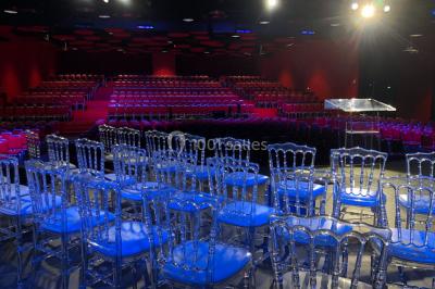 Bâtiment moderne en bord de rivière, entouré de verdure, avec un pont piétonnier au premier plan.
