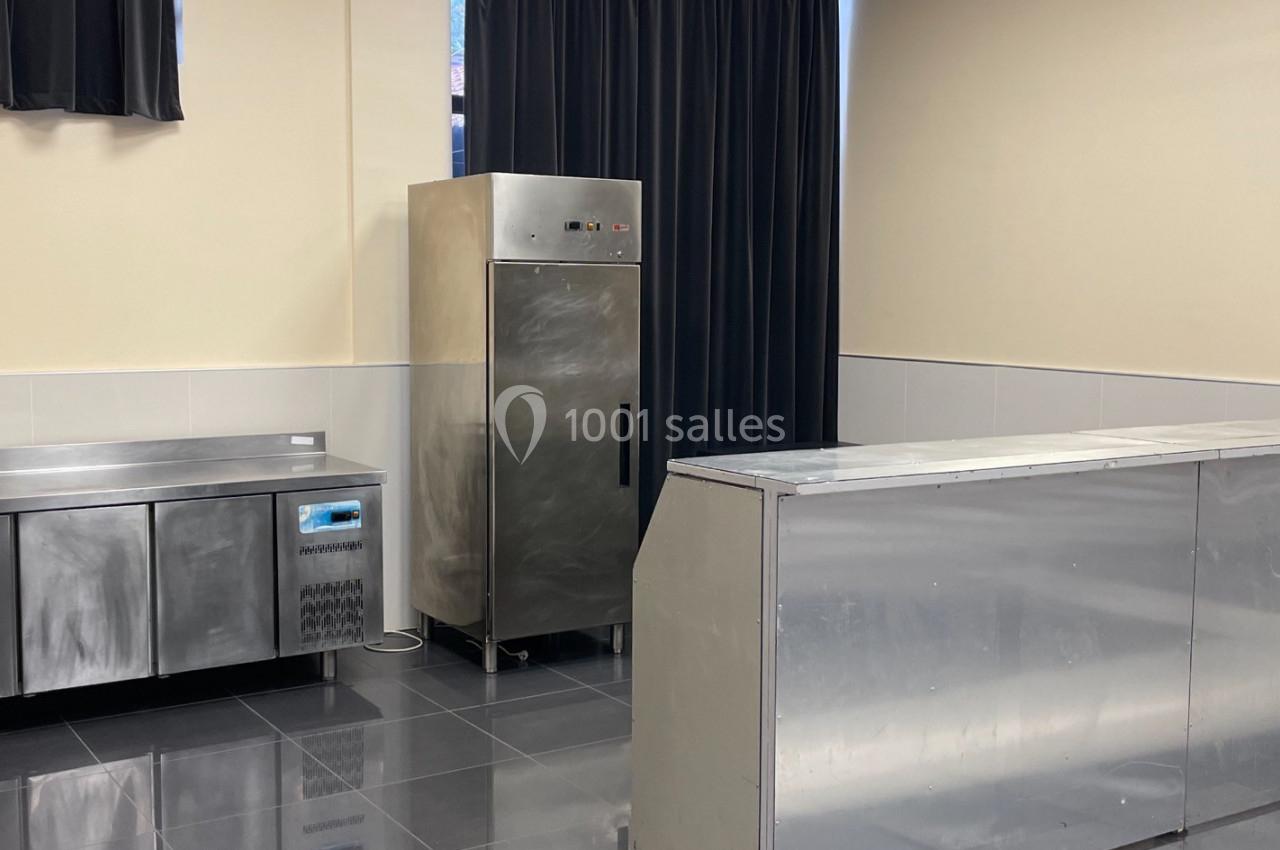 Cuisine professionnelle avec plan de travail en inox, armoire réfrigérée et murs clairs.