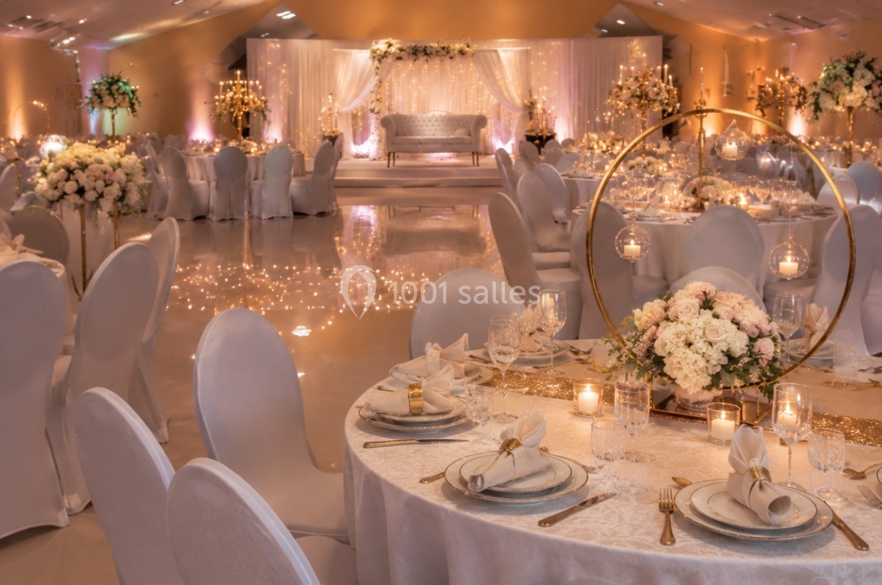 Salle de réception élégante décorée de fleurs, bougies et tables dressées pour un événement formel.