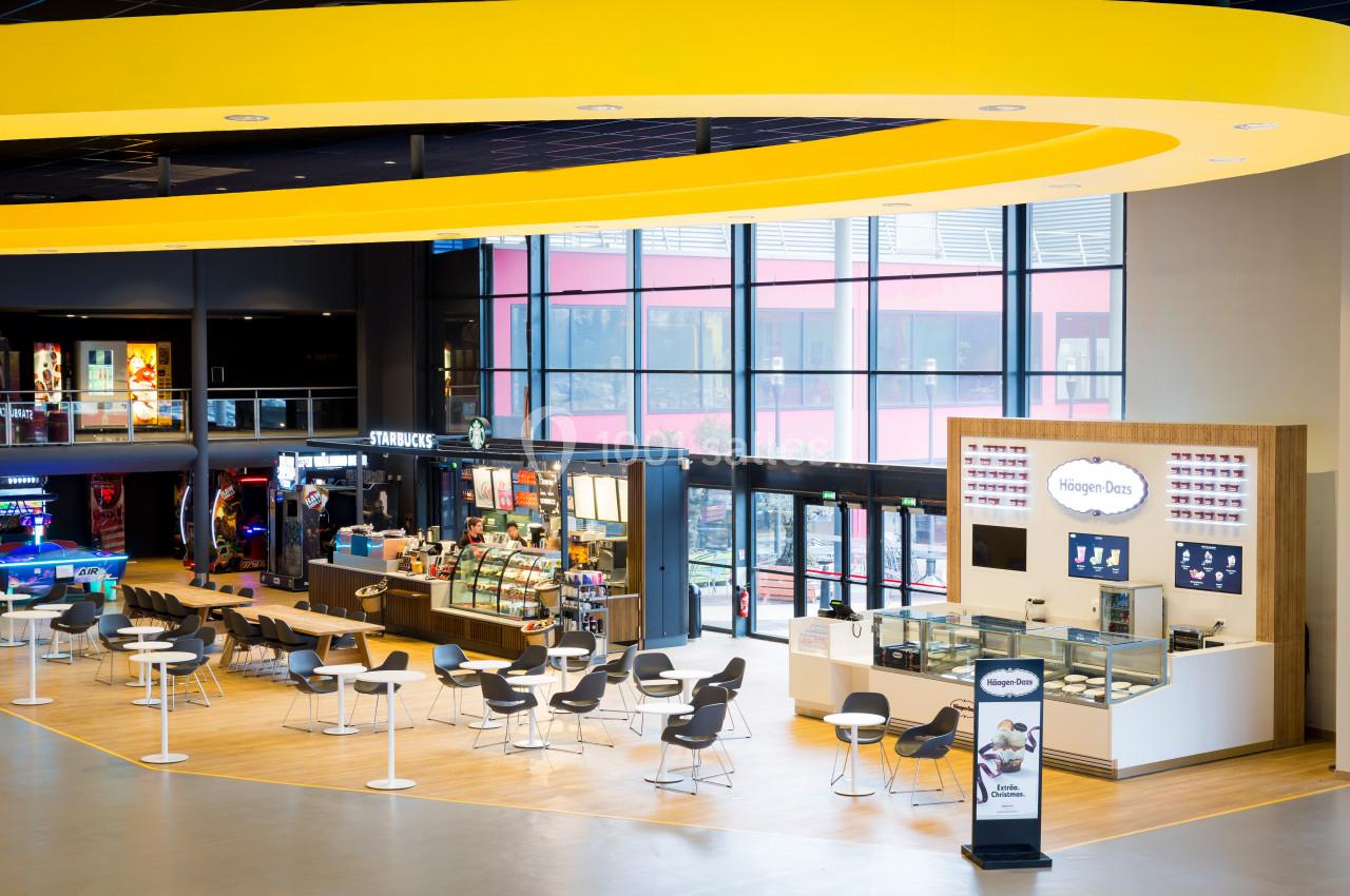 Espace de restauration moderne avec comptoirs Starbucks et Häagen-Dazs, tables et chaises dans un cadre lumineux.