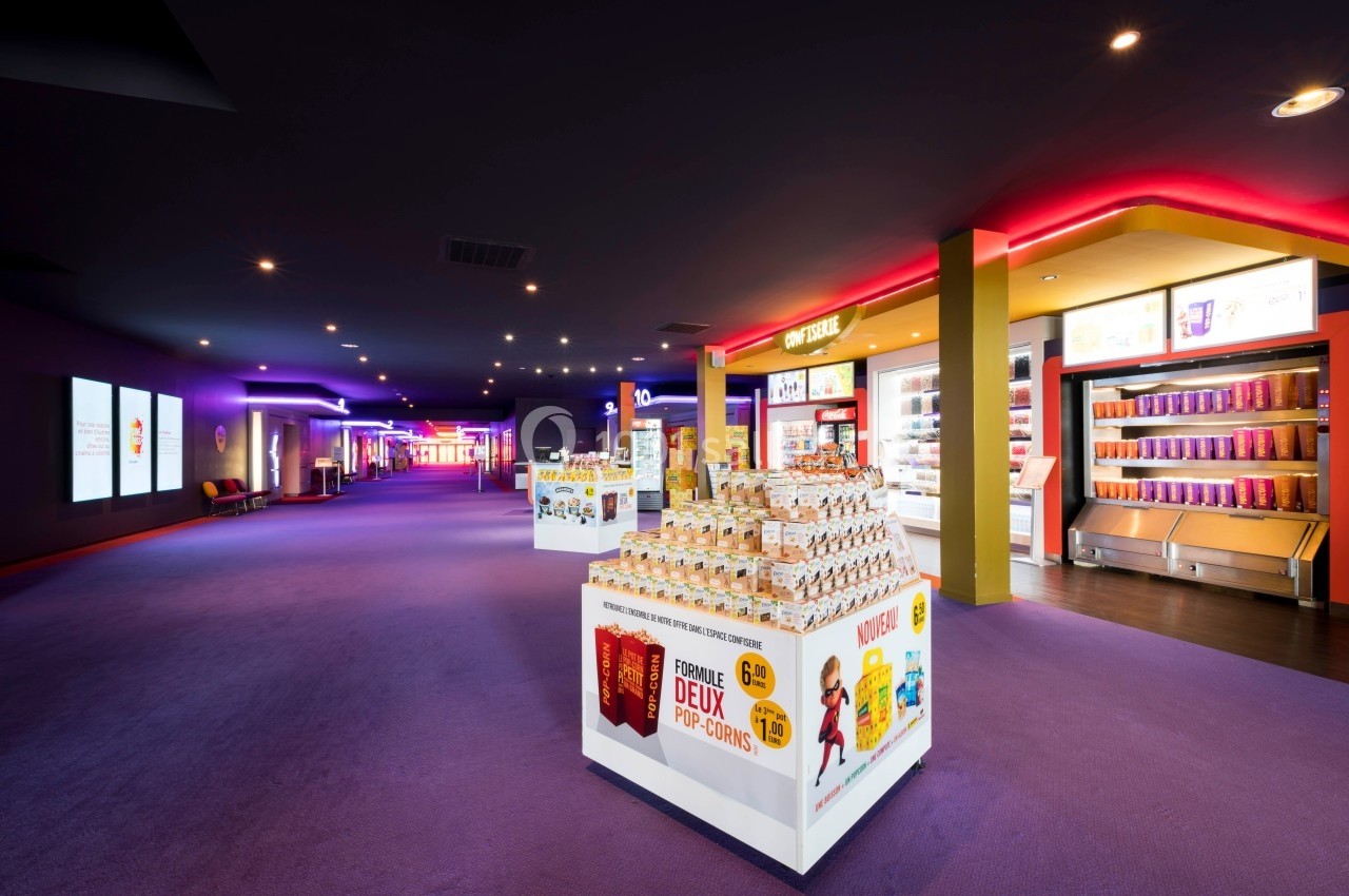 Location salle Dammarie-les-Lys (Seine-et-Marne) - Pathé Dammarie #3 Présentoirs de confiseries et boissons dans le hall lumineux d'un cinéma avec éclairage coloré.