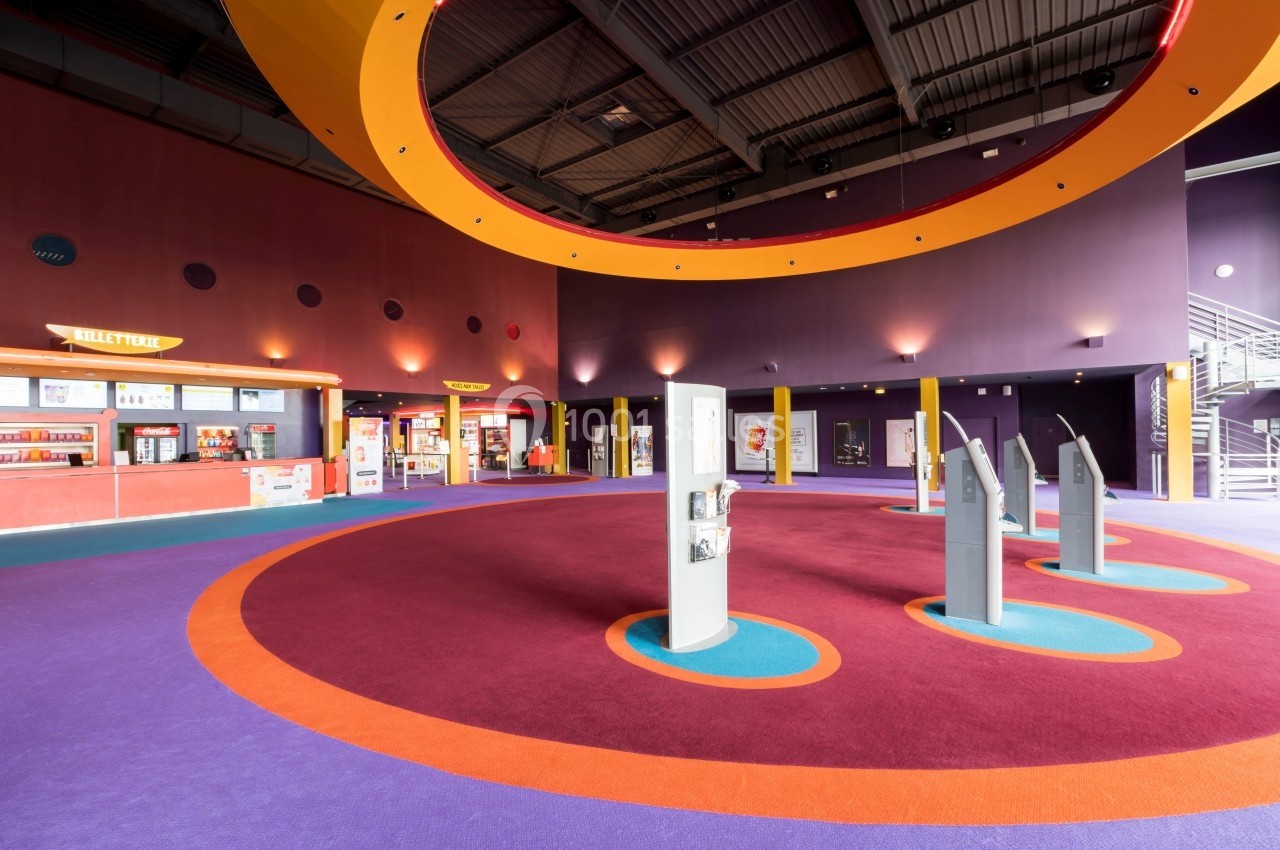 Location salle Dammarie-les-Lys (Seine-et-Marne) - Pathé Dammarie #5 Hall d'entrée spacieux avec guichets, bornes interactives et éclairage coloré sous un plafond industriel.