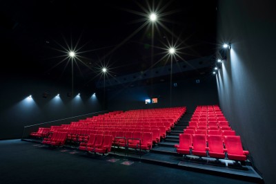 Miniature Location salle Dammarie-les-Lys (Seine-et-Marne) - Pathé Dammarie #9 Salle de cinéma vide avec des rangées de sièges rouges et un projecteur allumé au fond.