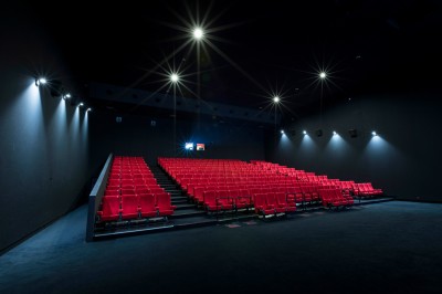 Miniature Location salle Dammarie-les-Lys (Seine-et-Marne) - Pathé Dammarie #10 Salle de cinéma vide avec des rangées de sièges rouges et un projecteur allumé au fond.
