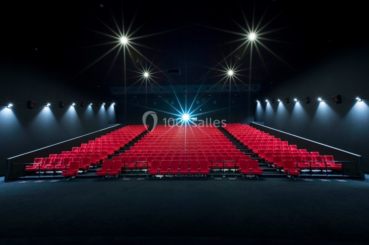 Location salle Dammarie-les-Lys (Seine-et-Marne) - Pathé Dammarie #15 Salle de cinéma vide avec des rangées de sièges rouges et un projecteur allumé au fond.