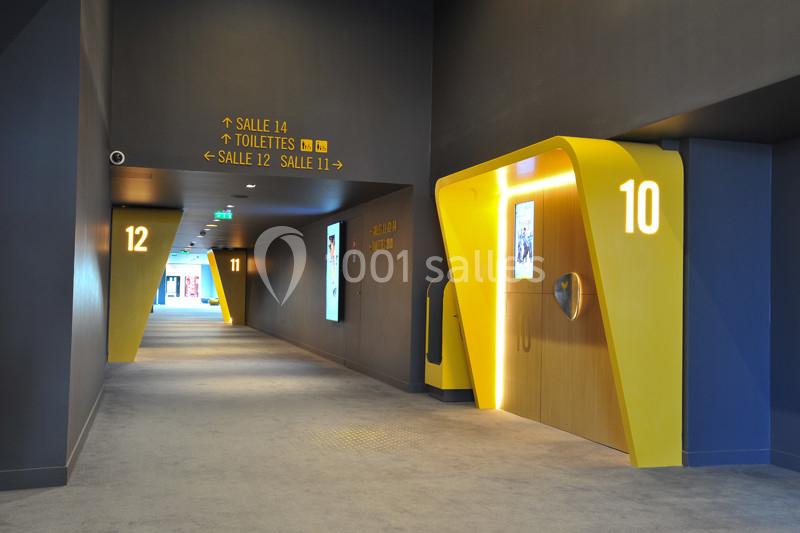 Couloir moderne avec signalétique lumineuse jaune indiquant les salles de cinéma 10 et 12, et des panneaux directionnels.