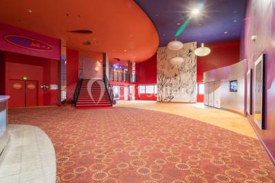 Miniature Location salle Champs-sur-Marne (Seine-et-Marne) - Pathé Disney Village #3 Salle de cinéma vide avec des rangées de sièges rouges, éclairage tamisé et écran en fond.